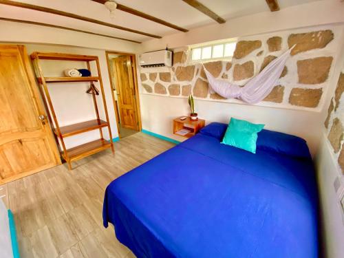 a bedroom with a blue bed and a stone wall at Casa de Orion in Ayangue