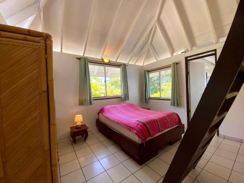 a small bedroom with a bed and two windows at MOOREA - Fare Tiki Beach in Haapiti