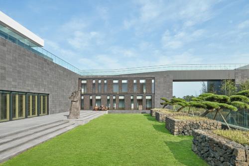 a building with a green lawn in front of it at JW Marriott Jeju Resort & Spa in Seogwipo