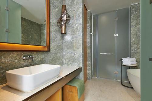 ein Badezimmer mit einem weißen Waschbecken und einem Spiegel in der Unterkunft The Westin Shimei Bay Resort in Wanning