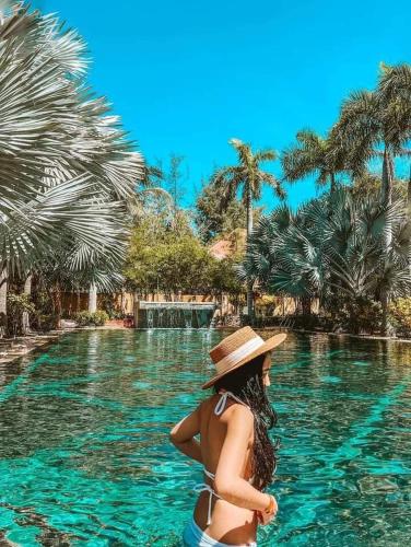 a woman in a hat standing in a swimming pool at Full Moon Village Resort in Mui Ne