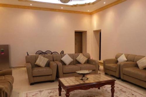 a living room with couches and a coffee table at Alnessayem Farmhouse in Sayḩ aş Şaqlah