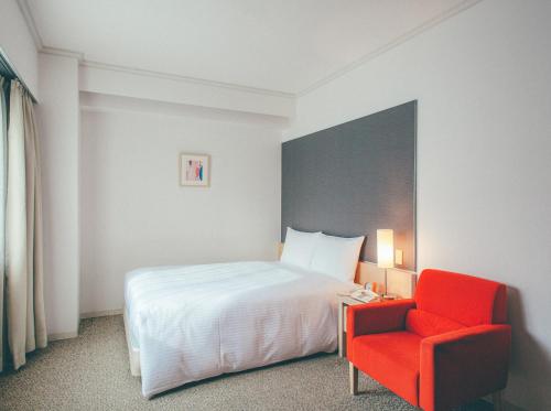 um quarto de hotel com uma cama e uma cadeira vermelha em Hamilton Hotel Red em Nagoia