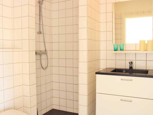 a white tiled bathroom with a sink and a shower at Holiday home Nexø LX in Neksø