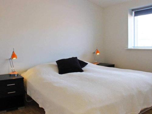 - une chambre dotée d'un lit blanc avec un oreiller noir dans l'établissement Holiday home Nexø LX, à Neksø
