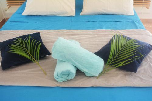 - une serviette bleue assise sur un lit avec 2 oreillers dans l'établissement Maison Piscine et Plage à pieds St François, à Saint-François