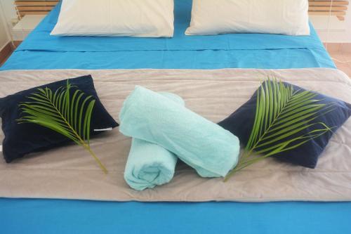 un asciugamano blu seduto su un letto con due cuscini di Bungalow La Papaye Bleue Résidence accès Piscine & Plage a Saint-François