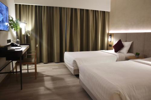 Habitación de hotel con 2 camas y escritorio en The Brunei Hotel, en Bandar Seri Begawan