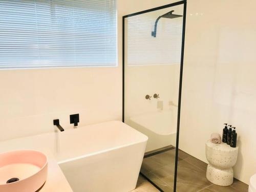 La salle de bains est pourvue d'une baignoire blanche et d'un lavabo. dans l'établissement The Blush House, à Hobart