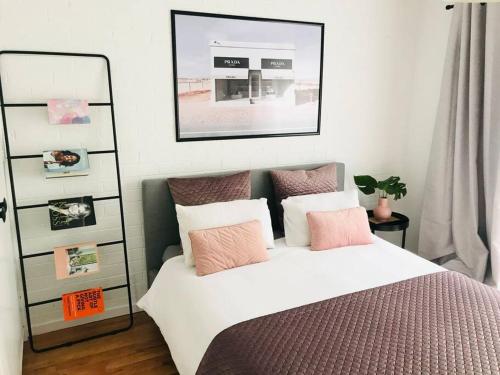 una camera da letto con un letto con cuscini rosa e bianchi di The Blush House a Hobart