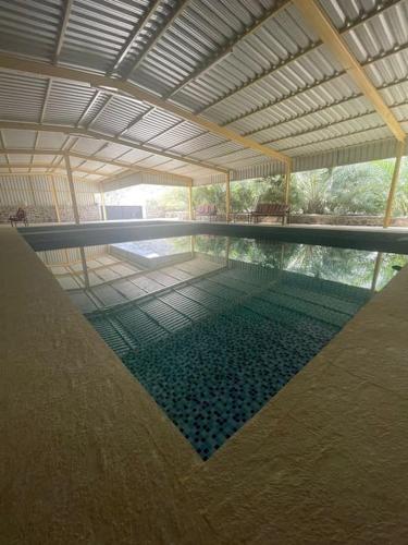 a swimming pool in a building with a roof at Alsalam Farmhouse in Hatta
