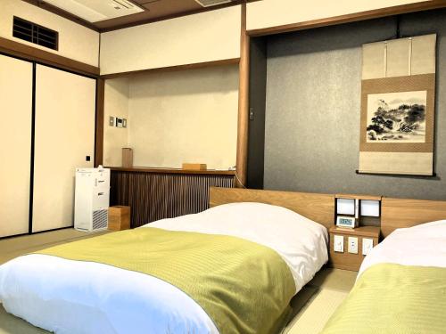 a bedroom with two beds and a large window at Shuzenji Onsen Katsuragawa in Izu