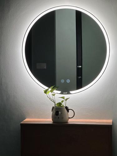 a circular mirror above a vase with a plant on a table at Liang's Home เหลียงโฮม in Ban Riang