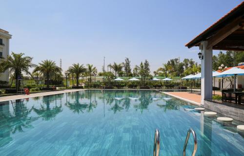 a large blue swimming pool with umbrellas in a resort at The Harmonia in Quang Ngai