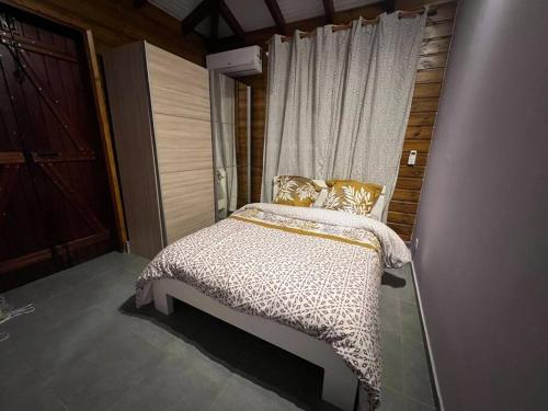 Un dormitorio con una cama con almohadas de oro y una ventana en Charmante Villa, kaz’ AA.Liyah, en Pointe-à-Pitre