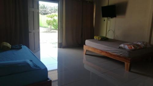 a bedroom with two beds and a sliding glass door at Cabinas Lawson in Puerto Jiménez