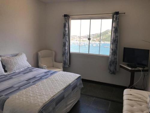 a bedroom with a bed and a window with a view of the ocean at Pousada Recanto Marinho in Arraial do Cabo