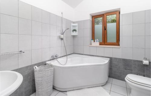 a white bathroom with a tub and a toilet at Lovely Home In Dolinci With Outdoor Swimming Pool in Grižane