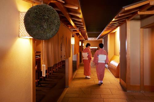 two women walking down a hallway in a building at Shinagawa Prince Hotel in Tokyo