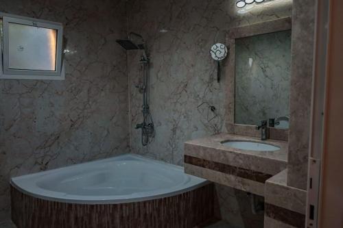 ein Badezimmer mit einer Badewanne, einem Waschbecken und einem Spiegel in der Unterkunft Hatta Orchard in Hatta