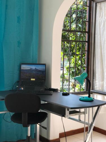 einen Schreibtisch mit einem Laptop und einem Stuhl vor einem Fenster in der Unterkunft Full Apartamento en Medellin Itagui Centro de la moda Mayorista Poblado in Itagüí
