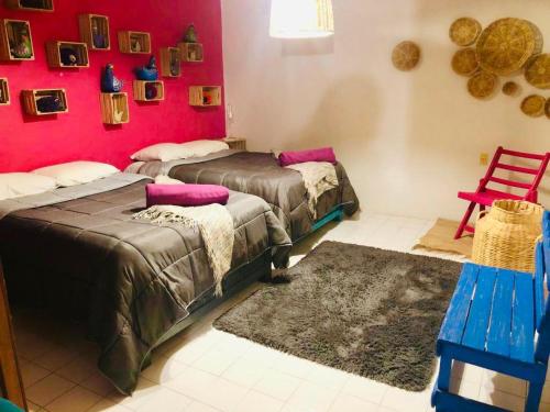 a room with two beds and a red wall at DEPARTAMENTO EN SAN CRISTOBAL Centro ESTACIONAMIENTO LUGARES PUBLICOS EN LA CALLE in San Cristóbal de Las Casas