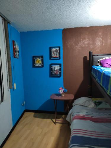 1 dormitorio con paredes azules, 1 cama y 1 mesa en Departamento de huéspedes Grijalva, en Ciudad de México