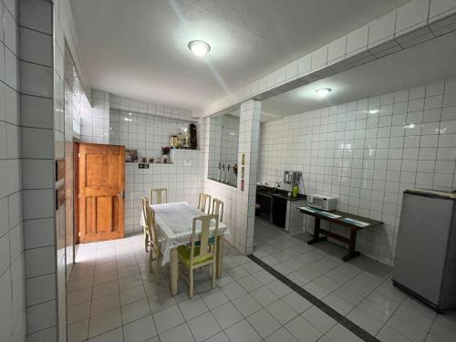 a white tiled kitchen with a table and a small kitchen with a tablektop at Hostel Alto do Rosario in Vitória