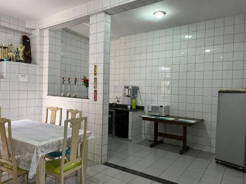 a white tiled kitchen with a table and a table and chairs at Hostel Alto do Rosario in Vitória