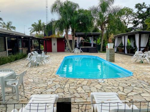 a swimming pool with chairs and a table and a building at POUSADA DELVILLE in Itapoa