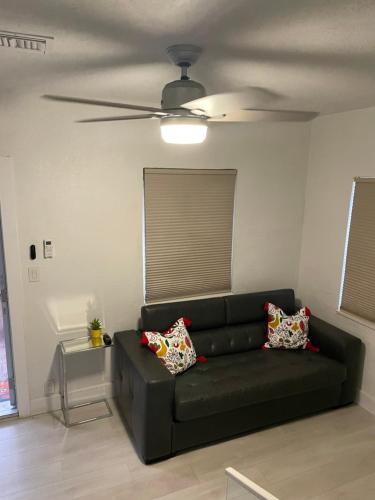 a black couch in a living room with a ceiling fan at Comfortable modern apartment- central location. in Miami
