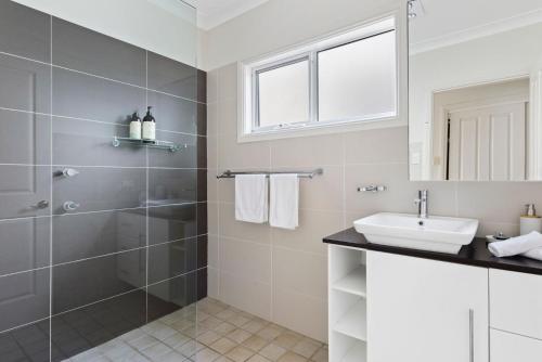 a bathroom with a shower and a sink at Beachwood House at Mollymook Beach in Mollymook
