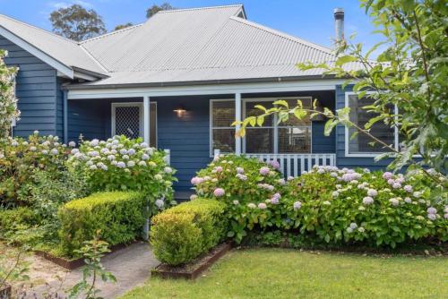 a blue house with flowering bushes in front of it at Countryside Luxe in Milton