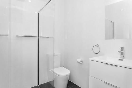 a bathroom with a toilet and a glass shower at Pas Beach House Apartment 2 in Mollymook