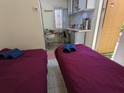 2 posti letto in una piccola camera con coperte viola di חדר אירוח צפתי לזוג a Safed