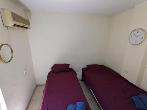 two beds in a room with a clock on the wall at חדר אירוח צפתי לזוג in Safed