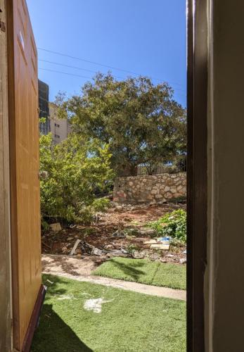 an open door to a yard with a stone wall at חדר אירוח צפתי לזוג in Safed