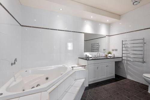 Un baño blanco con bañera y lavabo. en Aqua Shores Apartment, en Mollymook