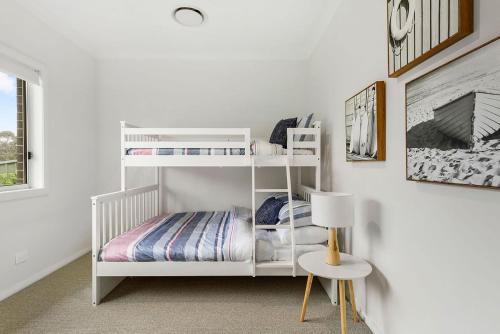 a white bunk bed in a white room with a lamp at Gone Coastal at Narrawallee in Narrawallee
