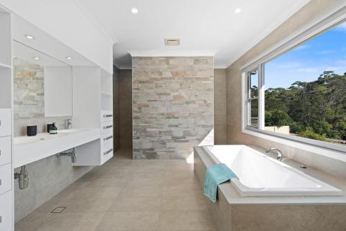 een badkamer met een groot bad en een raam bij Kookaburra Heights in Mollymook