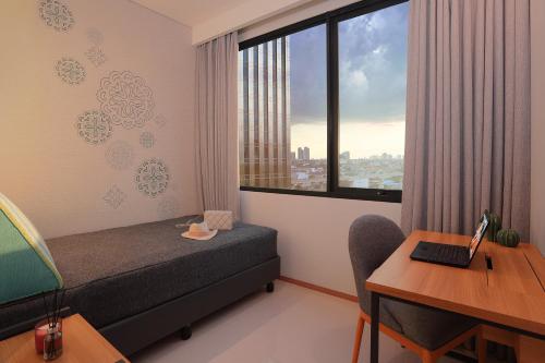 a bedroom with a bed and a desk and a window at Citadines Gatot Subroto Jakarta in Jakarta