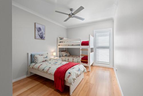een slaapkamer met 2 stapelbedden en een plafondventilator bij Kookaburra Heights in Mollymook
