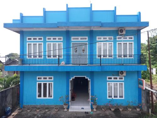 ein blaues Haus mit einem Balkon und einer Tür in der Unterkunft Tangkoko Gallery Guest House and Resto in Rinondoran