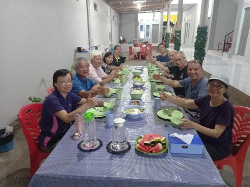 eine Gruppe von Menschen, die an einem Tisch mit Essen sitzen in der Unterkunft Tangkoko Gallery Guest House and Resto in Rinondoran