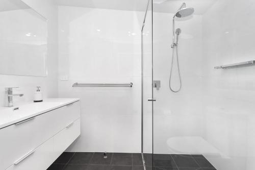 a white bathroom with a shower and a sink at Pas Beach House Apartment 1 in Mollymook