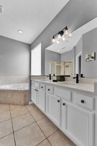 a large bathroom with white cabinets and a tub at Magical Retreat in Kissimmee