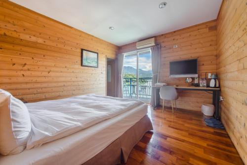 魚池鄉的住宿－碧水山居湖畔民宿，一间卧室设有木墙、一张床和电视