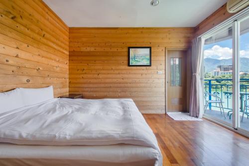 a bedroom with a bed and a large window at Bishui Shanju Lakeside B&B in Yuchi