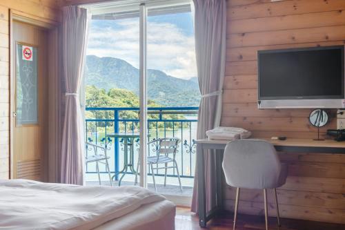 a bedroom with a bed and a desk and a large window at Bishui Shanju Lakeside B&B in Yuchi