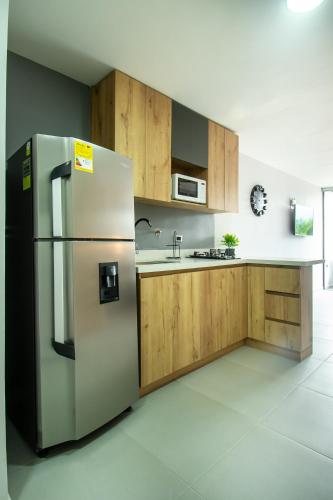 a kitchen with a stainless steel refrigerator and wooden cabinets at Barcelo Coliving in Medellín